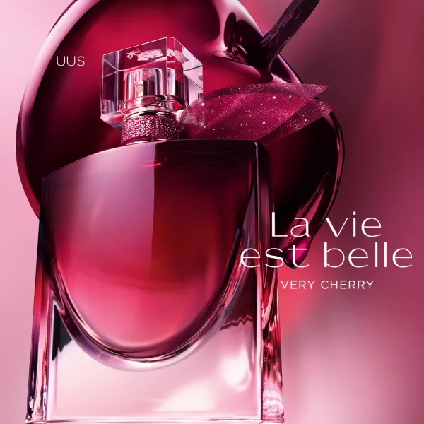 Lancôme La Vie Est Belle Very Cherry parfüümipudel kirsipunastes toonides dekoratiivsel roosal taustal.