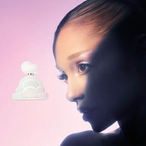 Pilvekujuline Ariana Grande Cloud parfüümipudel inimese näoprofiili kõrval pehmel roosal taustal.