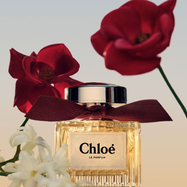 Punase lindiga Chloé Le Parfumi pudel, mida ümbritsevad punased ja valged lilled, loob luksusliku ja romantilise kuvandi.