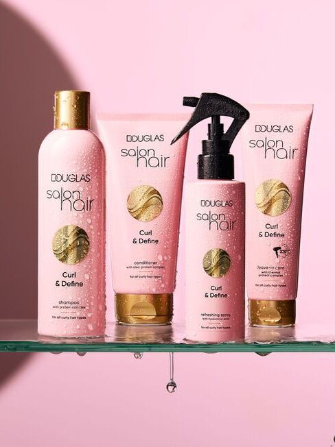 Neljast roosast pudelist koosnev komplekt kuldsete korkidega, Douglas Salon Hair Curl & Define, lokkis juustele, sh šampoon, palsam, sprei ja hooldusvahend.